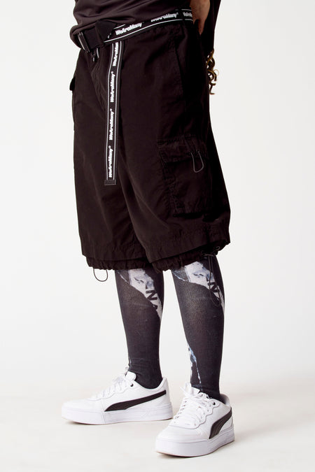 Short noir de COELY, associé à une legging imprimée et des baskets blanches.