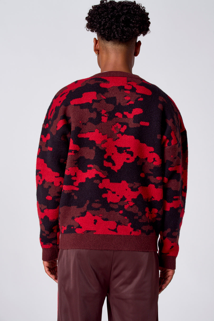 Rode trui met ronde hals van COELY, met een camouflagepatroon in rood, bruin en zwart.