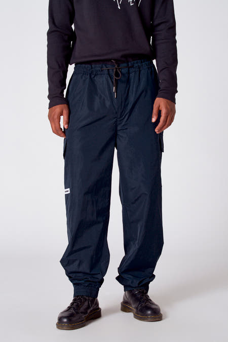 Donkerblauwe cargobroek van COELY, met trekkoord en elastische enkels, gedragen met een zwarte longsleeve en zwarte schoenen.
