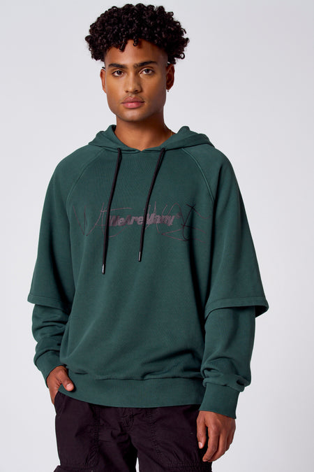 Groene sweatshirt met kap van COELY, met opschrift en gedragen met een zwarte broek.