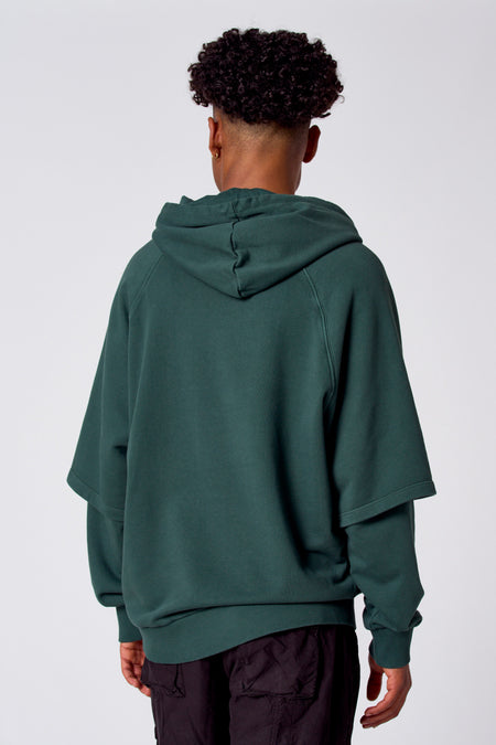 Groene sweatshirt met kap van COELY, gezien van achteren met korte mouwen en een donkere broek.