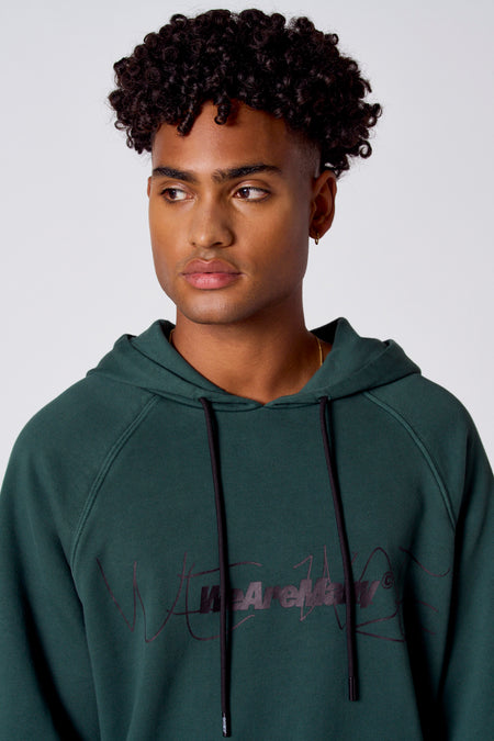 Groene sweatshirt met kap van COELY, met zwarte koorden en gedetailleerd opschrift op de voorkant.
