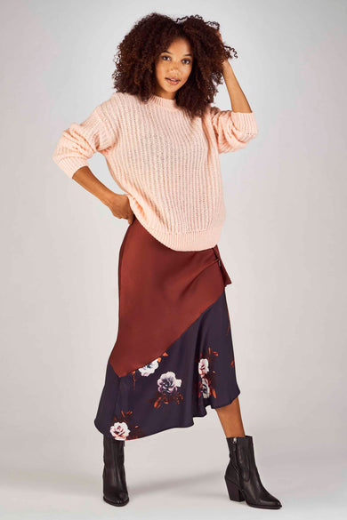 Bordeaux rok van Clouds of Fashion met bloemenprint, gecombineerd met een gebreide trui en zwarte laarzen.
