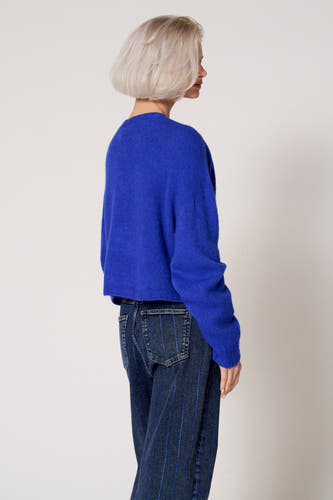 Blauwe trui met ronde hals van Clouds of Fashion, met donkerblauwe jeans met verticale strepen.
