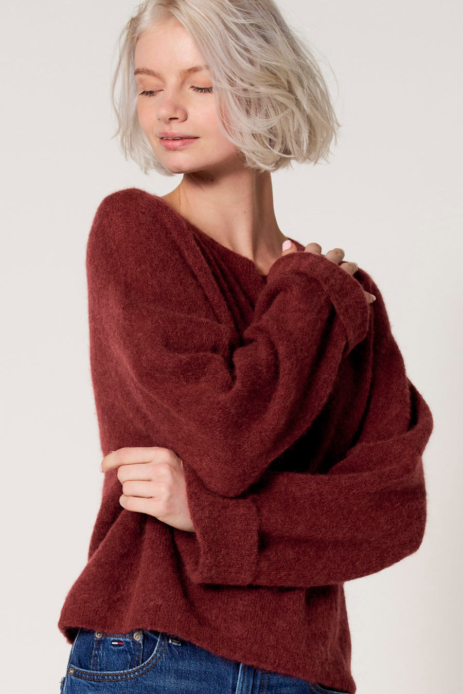 Bordeaux trui met ronde hals van Clouds of Fashion, met lange mouwen en zichtbare jeans.
