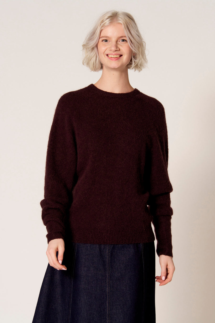 Bruine trui met ronde hals van Clouds of Fashion, gedragen met een donkerblauwe rok.
