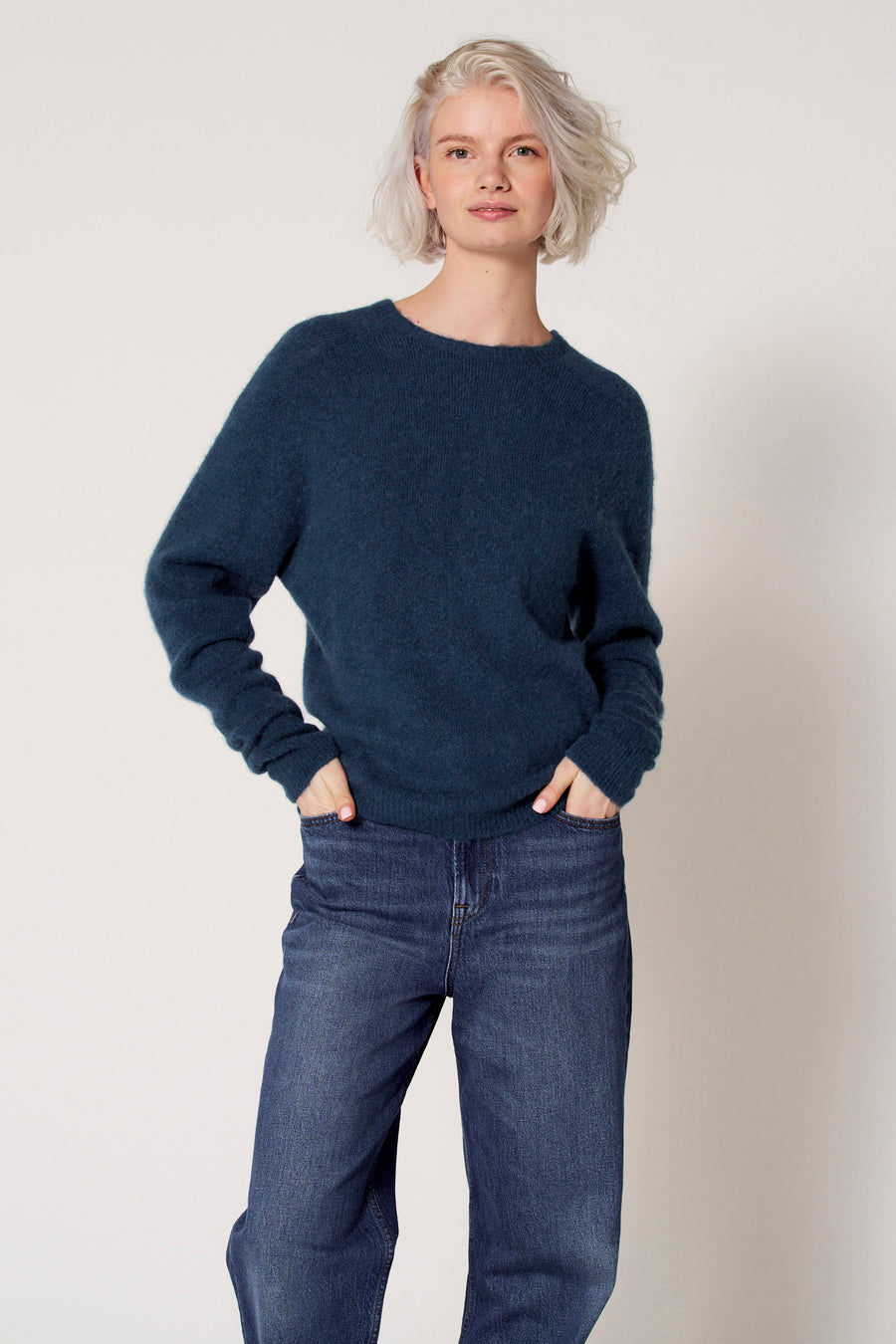 Blauwe trui met ronde hals van Clouds of Fashion, gedragen met jeans.