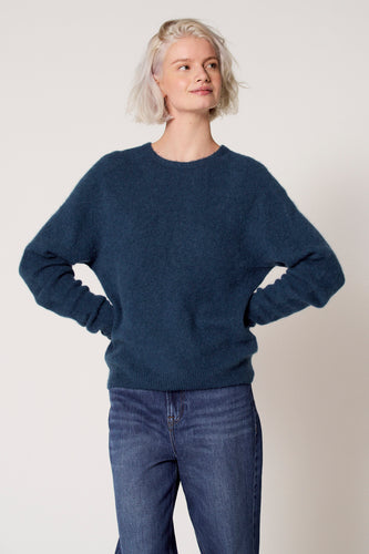 Blauwe trui met ronde hals van Clouds of Fashion, gedragen met een jeans.