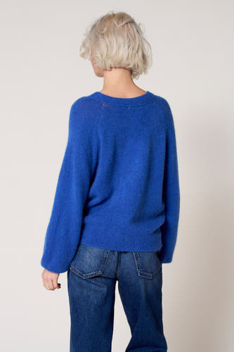 Blauwe V-hals trui van Clouds of Fashion, met lange mouwen en gecombineerd met een donkerblauwe jeans.
