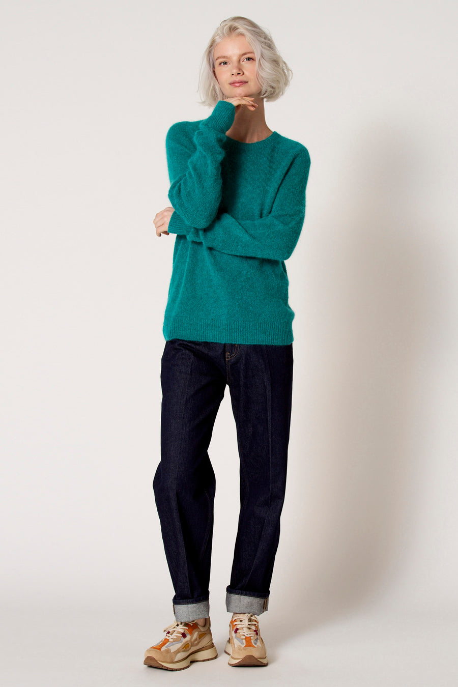 Groene trui met ronde hals van Clouds of Fashion, gedragen met donkere jeans en kleurrijke sneakers.
