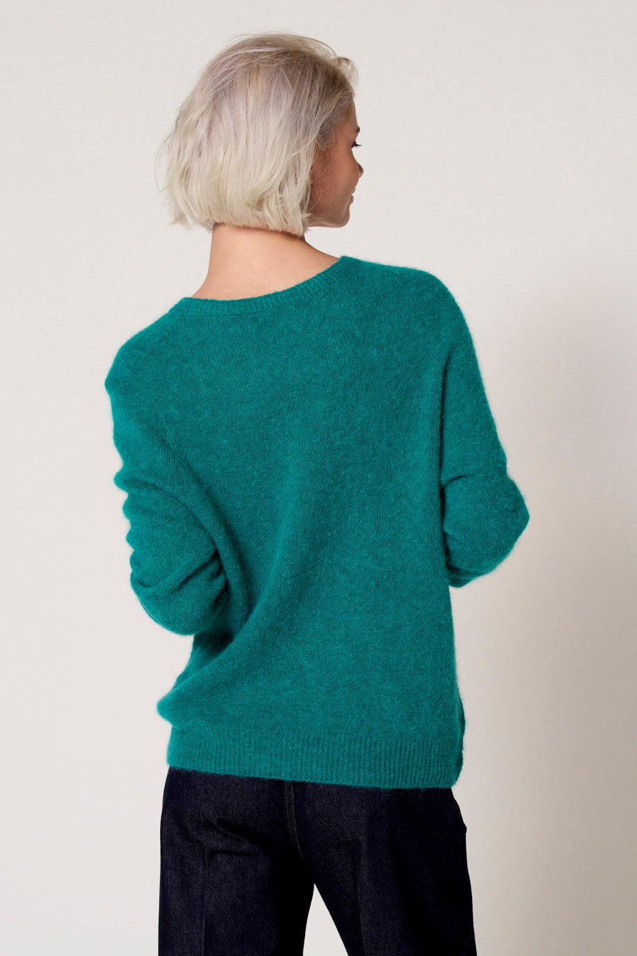 Groene trui met ronde hals van Clouds of Fashion, gezien van achteren, gecombineerd met een donkere spijkerbroek.
