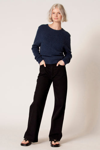 Blauwe trui met ronde hals van Clouds of Fashion, gedragen met zwarte broek en sandalen.