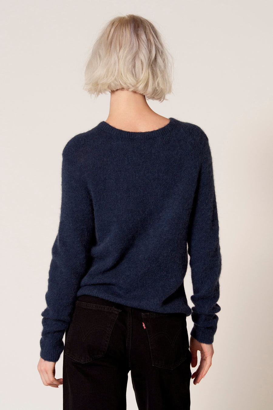 Blauwe trui met ronde hals van Clouds of Fashion, gezien van achteren, gecombineerd met een zwarte broek.
