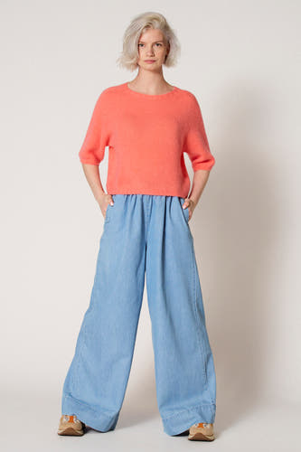 Roze trui met ronde hals van Clouds of Fashion, met wijde blauwe broek en crèmekleurige schoenen.