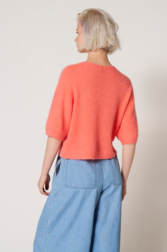 Roze trui met ronde hals van Clouds of Fashion, met korte mouwen en gedragen met een wijde jeansbroek.
