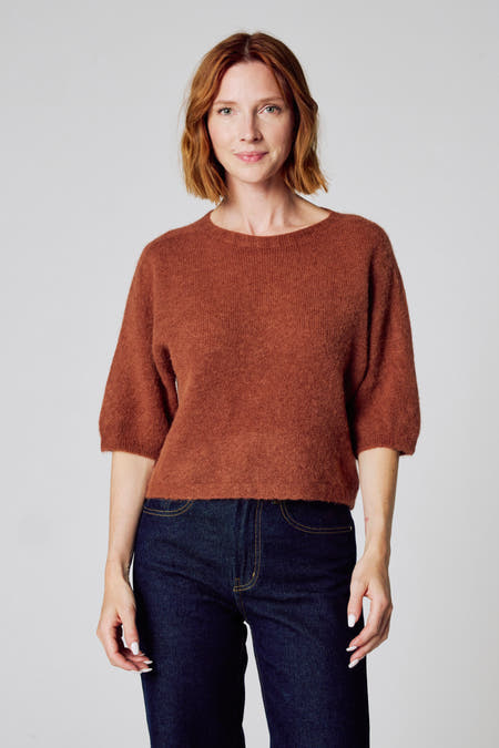 Bruine trui met ronde hals van Clouds of Fashion, gecombineerd met een donkere spijkerbroek.
