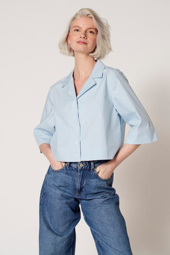 Chemisier bleu à manches trois-quarts de Clouds of Fashion, porté avec un jean à jambes larges.