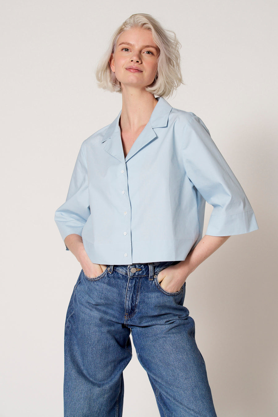 Chemisier bleu à manches trois-quarts de Clouds of Fashion, porté avec un jean à jambes larges.