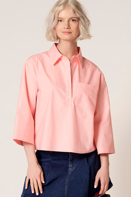 Chemisier rose à manches trois-quarts de Clouds of Fashion, avec une poche poitrine et porté avec une jupe bleu foncé.