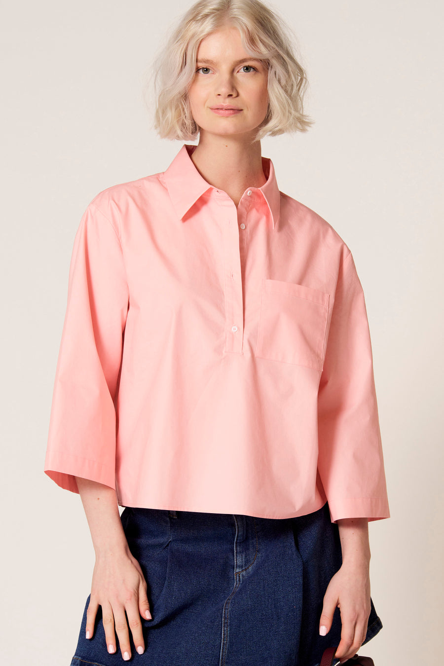 Roze blouse met driekwart mouwen van Clouds of Fashion, met een borstzak en gedragen met een donkerblauwe rok.
