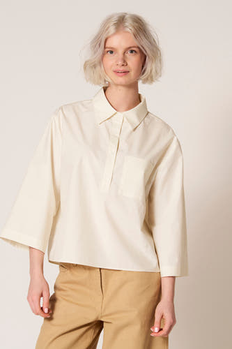 Witte blouse van Clouds of Fashion met driekwart mouwen en een borstzakje, gecombineerd met een bruine broek.