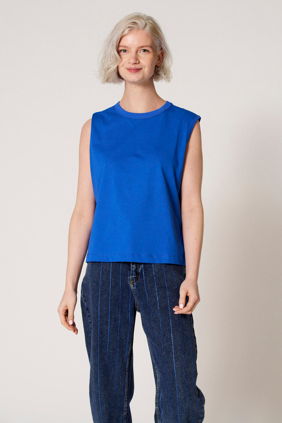 Blauwe singlet van Clouds of Fashion, gedragen met gestreepte denim broek.