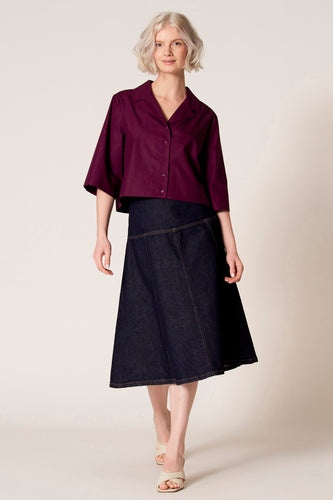 Paarse blouse met driekwart mouwen van Clouds of Fashion, gedragen met een donkerblauwe denim rok en beige sandalen.
