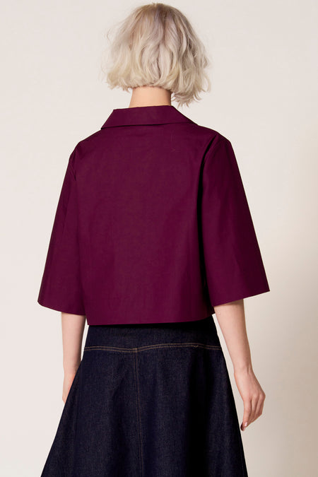 Paarse blouse met driekwart mouwen van Clouds of Fashion, gezien van achteren, gecombineerd met een donkerblauwe denim rok.
