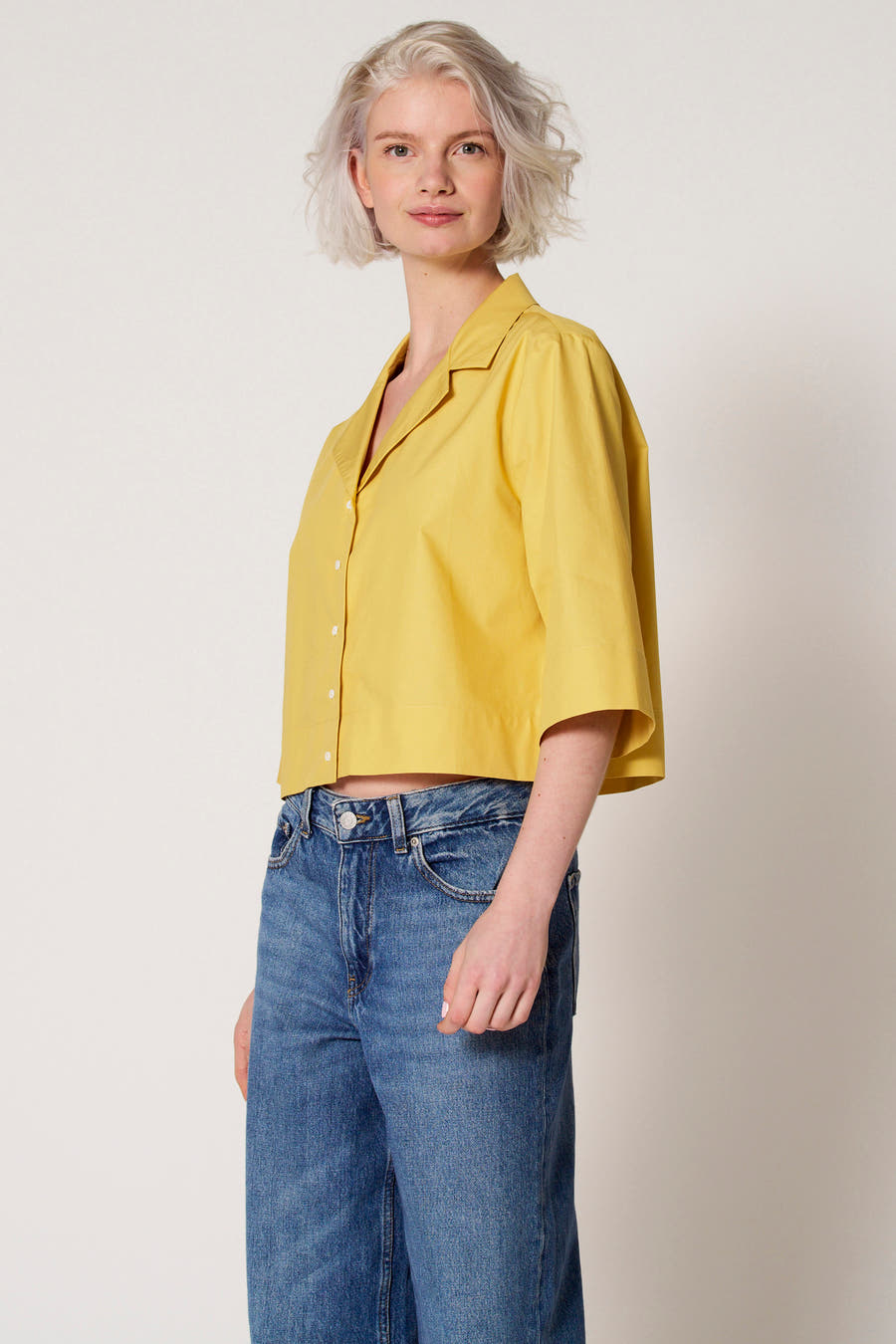 Gele blouse van Clouds of Fashion, met driekwart mouwen, gedragen met een blauwe jeansbroek.