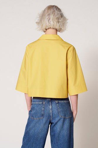 Gele blouse met driekwart mouwen van Clouds of Fashion, gezien van achteren, gecombineerd met een blauwe jeans.
