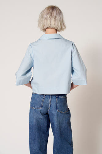Blouse bleue à manches trois-quarts de Clouds of Fashion, avec un col et associée à des jeans larges.