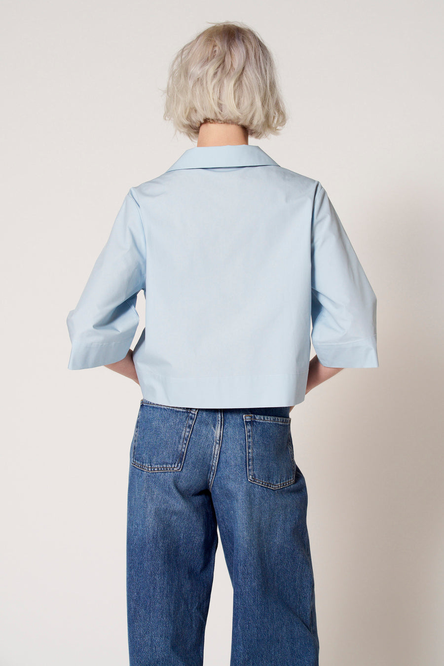 Blouse bleue à manches trois-quarts de Clouds of Fashion, avec un col et associée à des jeans larges.