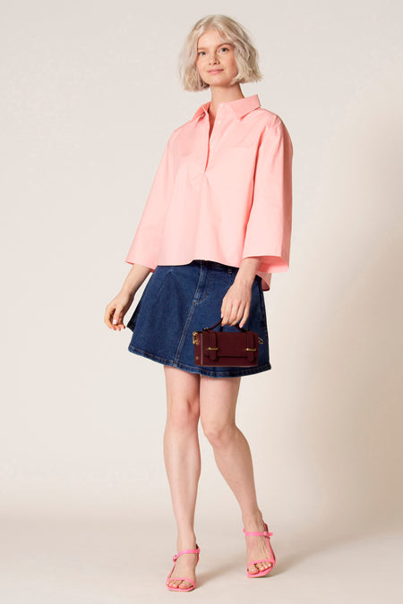 Blouse rose à manches trois-quarts de Clouds of Fashion, portée avec une jupe bleu foncé et des sandales roses.