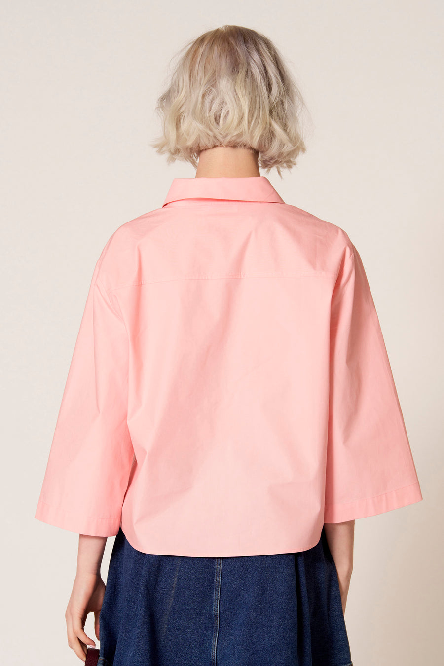 Roze blouse met driekwart mouwen van Clouds of Fashion, gezien van achter met een donkerblauwe rok.
