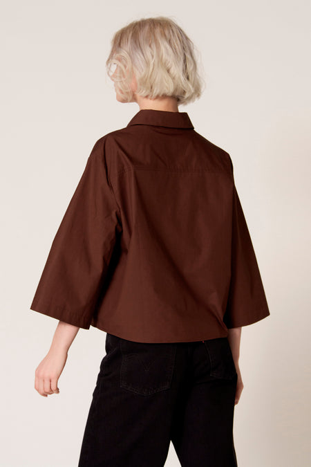 Bruine blouse van Clouds of Fashion, met driekwart mouwen, gedragen met een zwarte broek, achterkant weergegeven.
