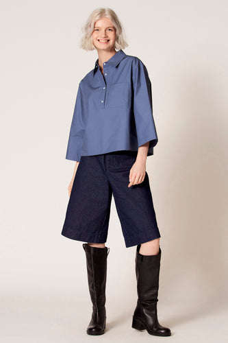 Blauwe blouse met driekwart mouwen van Clouds of Fashion, met een borstzak en gedragen met donkerblauwe culottes en zwarte laarzen.
