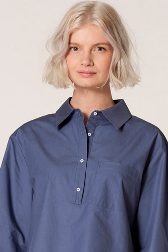 Blauwe blouse van Clouds of Fashion met een borstzak en witte knopen.