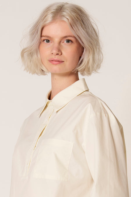Witte blouse van Clouds of Fashion, met lange mouwen en borstzak, gedragen door een model.

