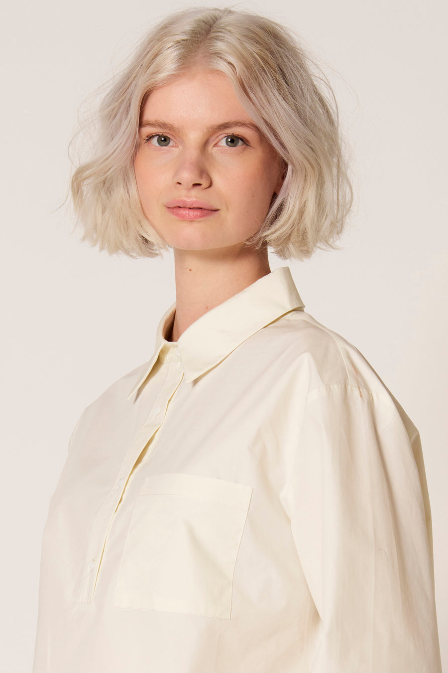 Witte blouse van Clouds of Fashion, met lange mouwen en borstzak, gedragen door een model.
