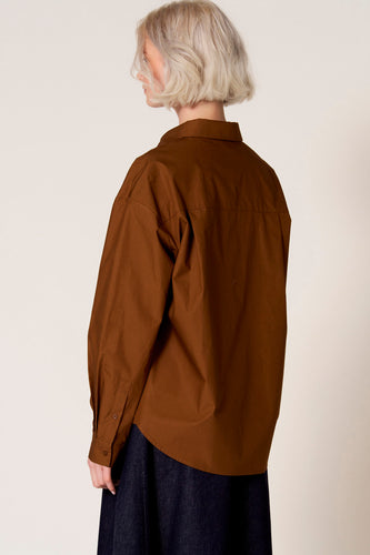 Bruine blouse met lange mouwen van Clouds of Fashion, met een klassieke kraag en lange mouwen gedragen met een donkerblauwe rok.
