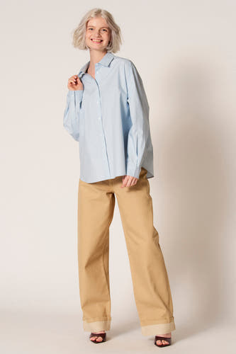 Chemisier bleu à manches longues de Clouds of Fashion, vu de dos, avec un pli subtil et un pantalon de couleur claire.