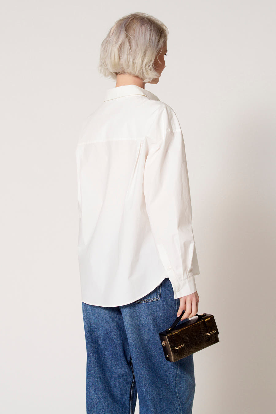 Witte blouse met lange mouwen van Clouds of Fashion, gedragen met een wijde jeans en een bruine tas.