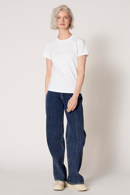 Wit T-shirt met korte mouwen van Clouds of Fashion, gedragen met gestreepte jeans en sneakers.
