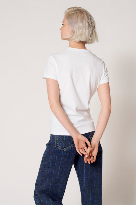 Wit T-shirt met korte mouwen van Clouds of Fashion, met een ronde hals en gedragen met donkere jeans met blauwe strepen.
