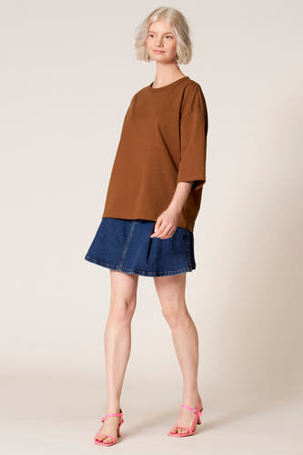 Bruin T-shirt met korte mouwen van Clouds of Fashion, gedragen met een spijkerrok en roze sandalen met hak.