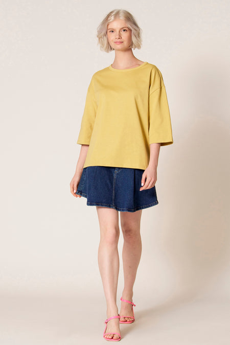 Geel T-shirt met korte mouwen van Clouds of Fashion, met een losse pasvorm en gecombineerd met een spijkerrok.