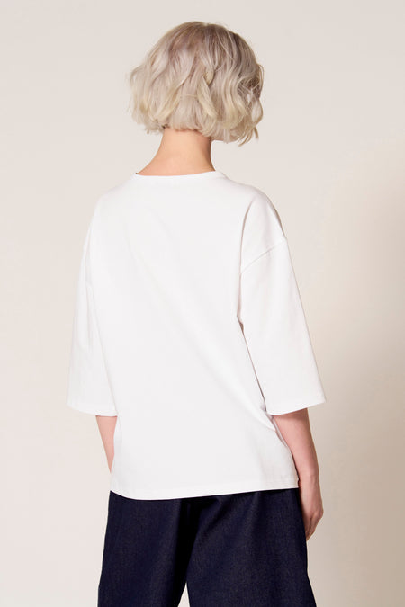 Wit T-shirt met korte mouwen van Clouds of Fashion, gezien van achteren, gedragen met donkerblauwe broek.