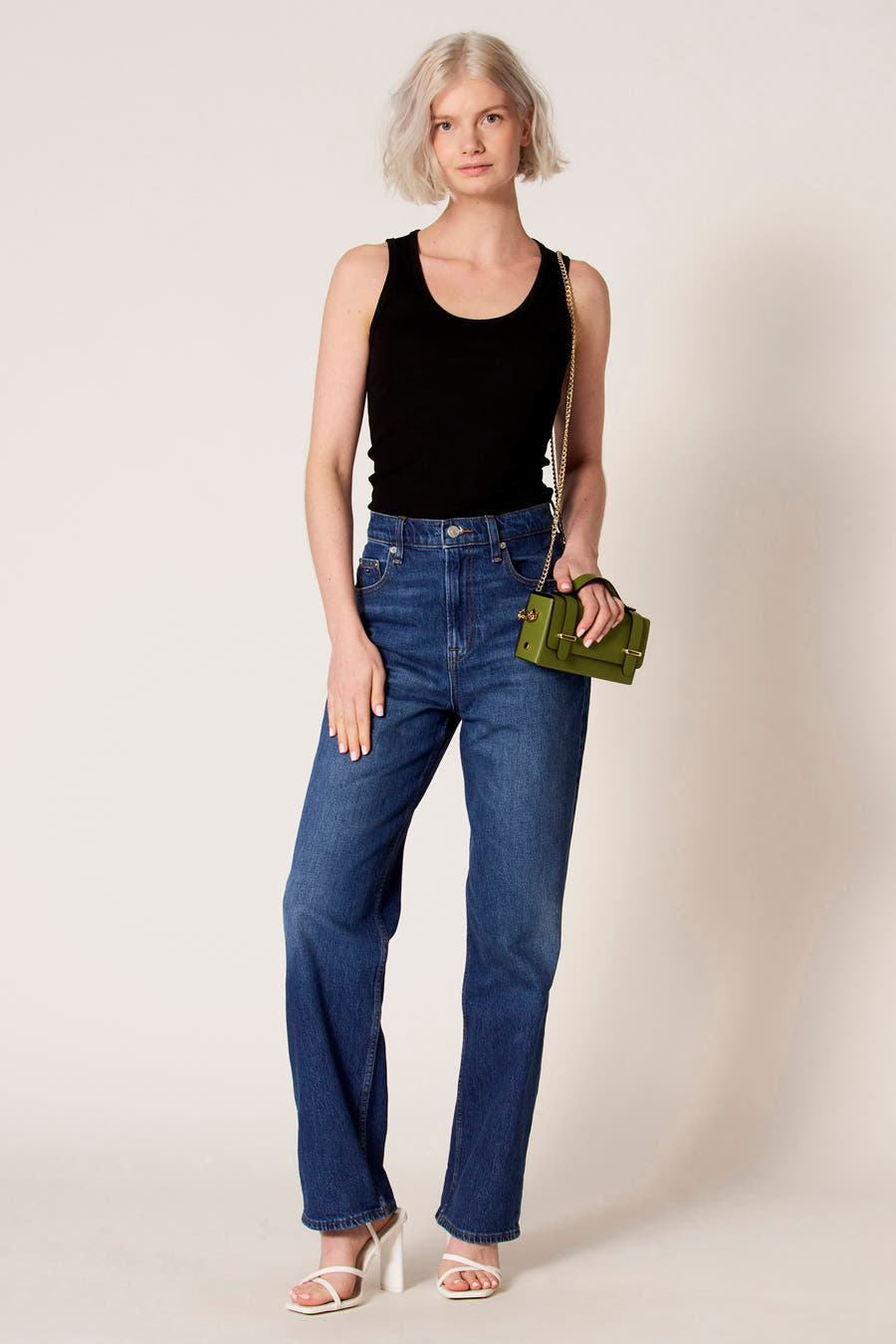 Zwarte singlet van Clouds of Fashion, gedragen met jeans en een groene tas met gouden details.
