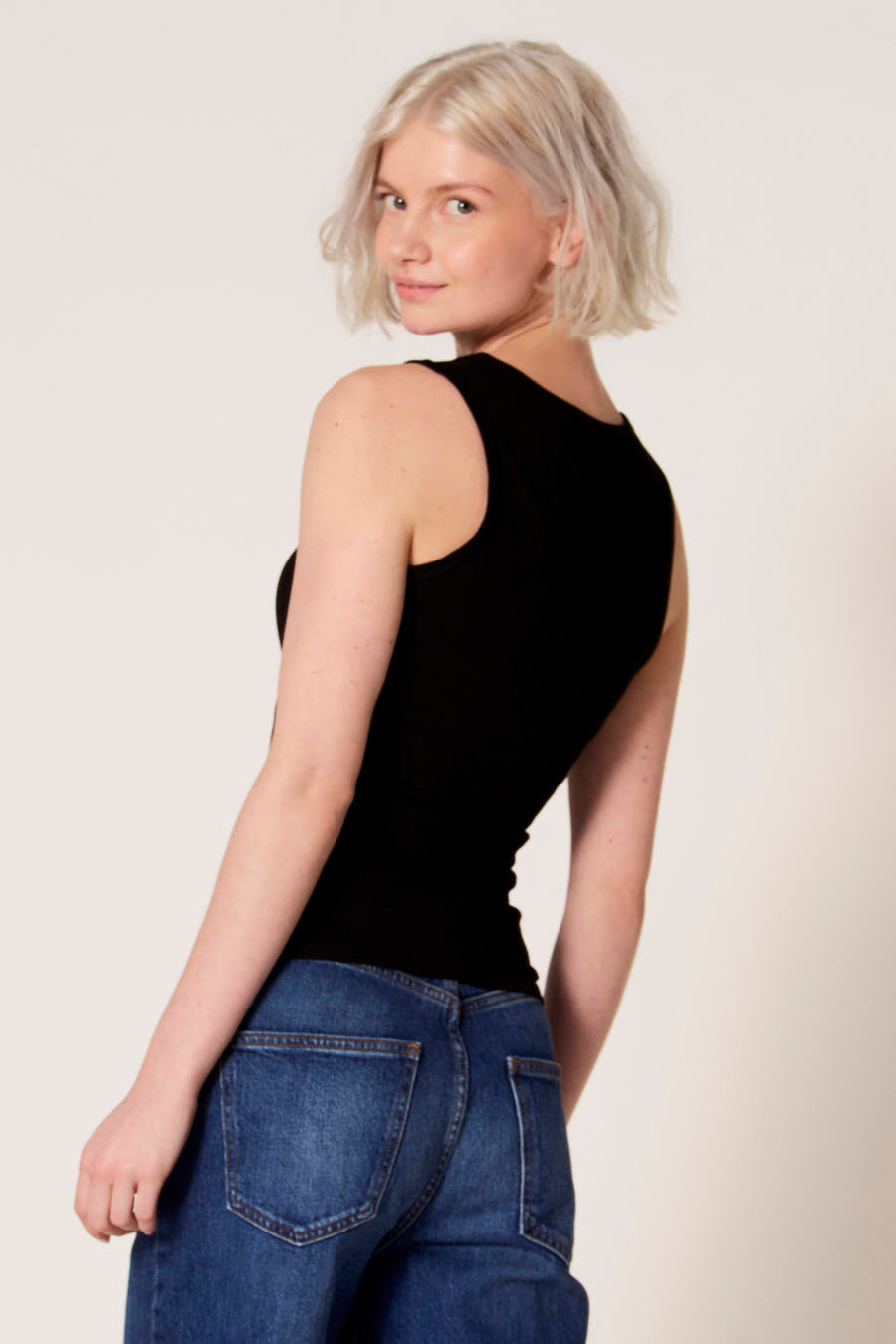 Zwarte singlet van Clouds of Fashion, met een strak model, gedragen met een blauwe jeans.