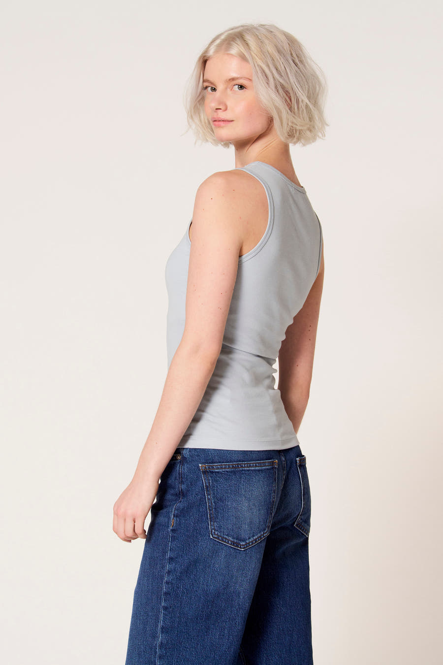 Blauwe singlet van Clouds of Fashion, met een ribgebreide textuur, gedragen met wijde jeans.
